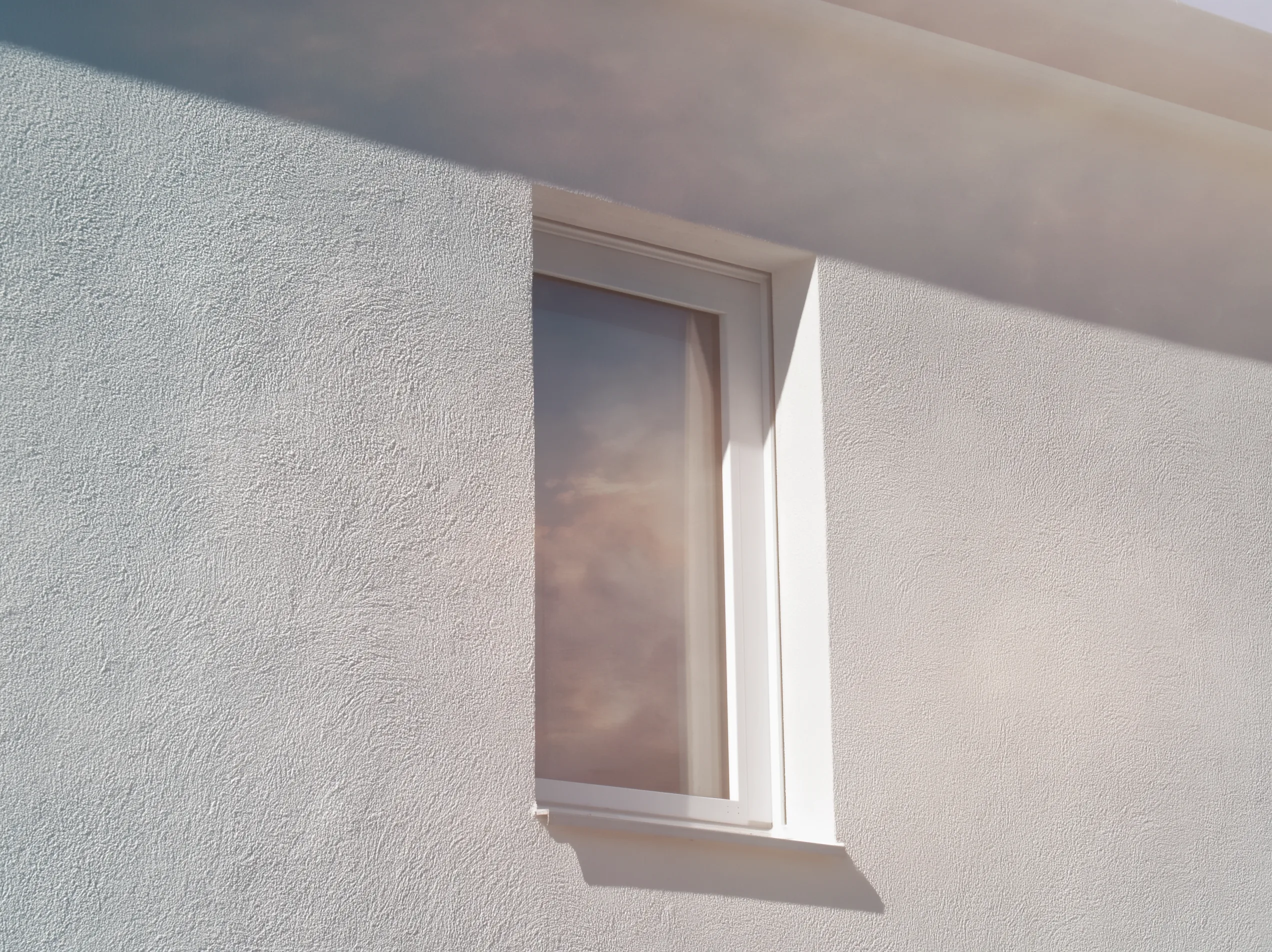 Witte gevel van een woning met buitenstucwerk